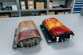 Comparaison entre un feu arrière Citroën Jumper usagé et une pièce de remplacement neuve posés sur un établi d'atelier