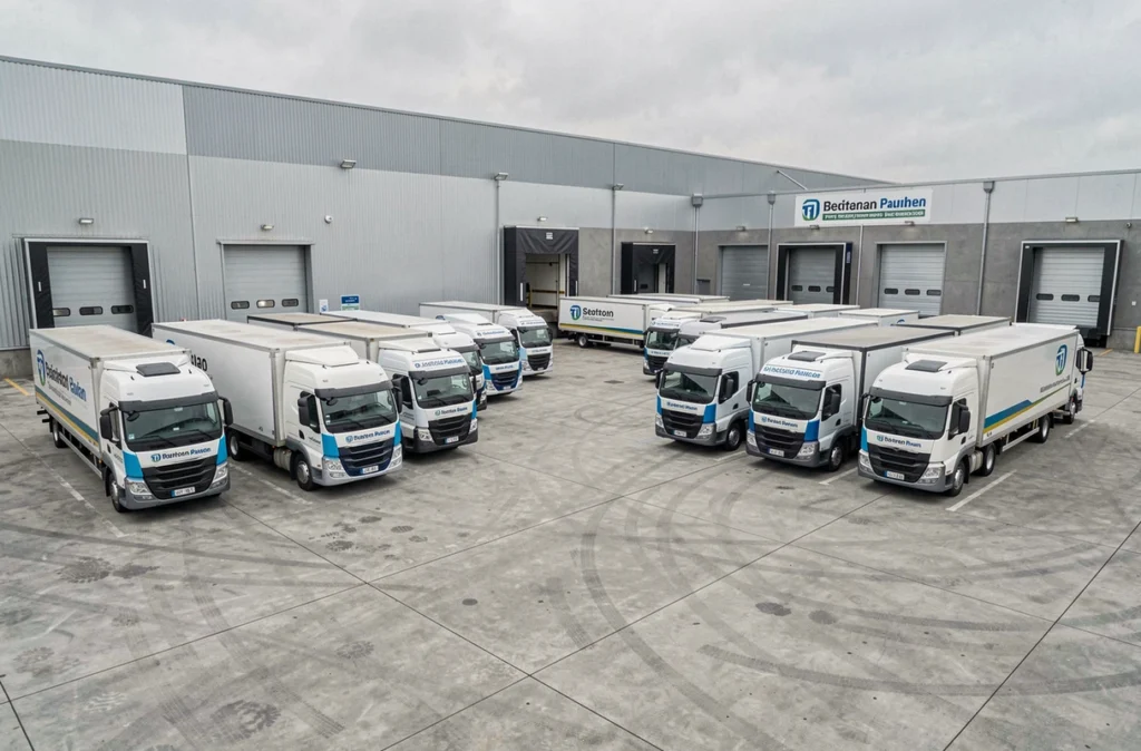 Vue grand angle d'une flotte de camions et fourgons d'entreprise de logistique garés dans un dépôt industriel